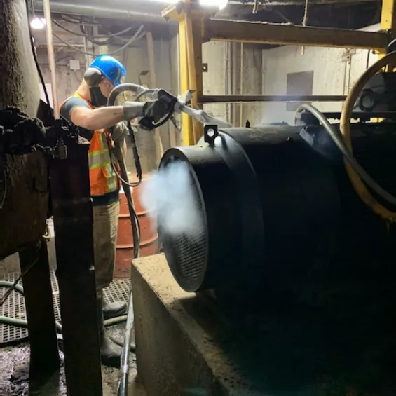 Worker using dry ice blasting at a pulp and paper mill