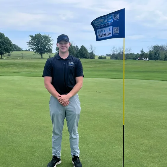 Mack from SZB Blasting & Coatings holding a flag at the June 2024 golf tournament.